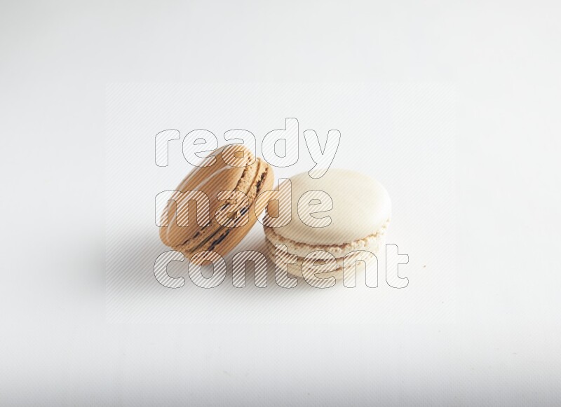 45º Shot of of two assorted Brown Irish Cream, and White Caramel fleur de sel macarons on white background