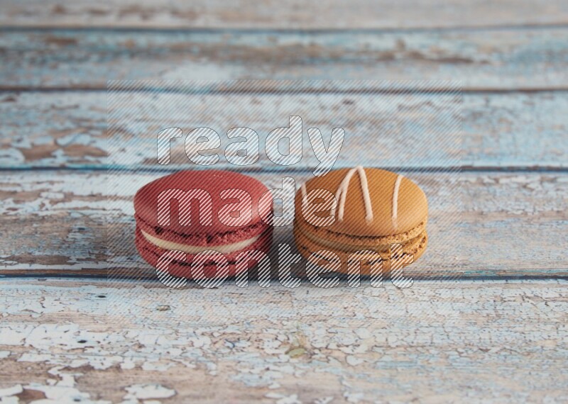 45º Shot of of two assorted Brown Irish Cream, and Red Velvet macarons on light blue background