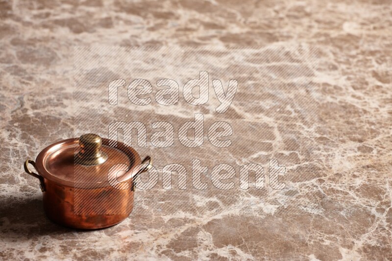 A small copper pot on beige marble background