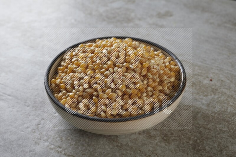 corn kernel in a multi-colored pottery bowl on a grey textured countertop