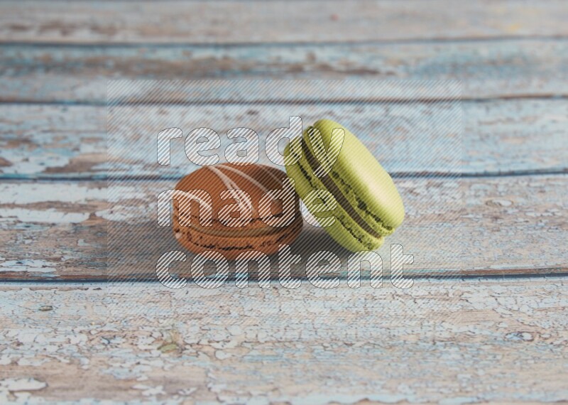45º Shot of of two assorted Brown Irish Cream, and Green Pistachio macarons  on light blue background