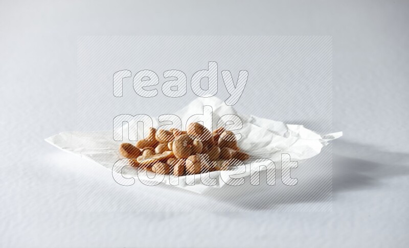 Cashews on a crumpled piece of paper on a white background in different angles