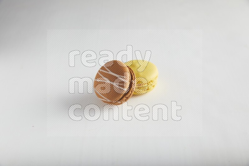 45º Shot of of two assorted Brown Irish Cream, and Yellow Lemon macarons on white background