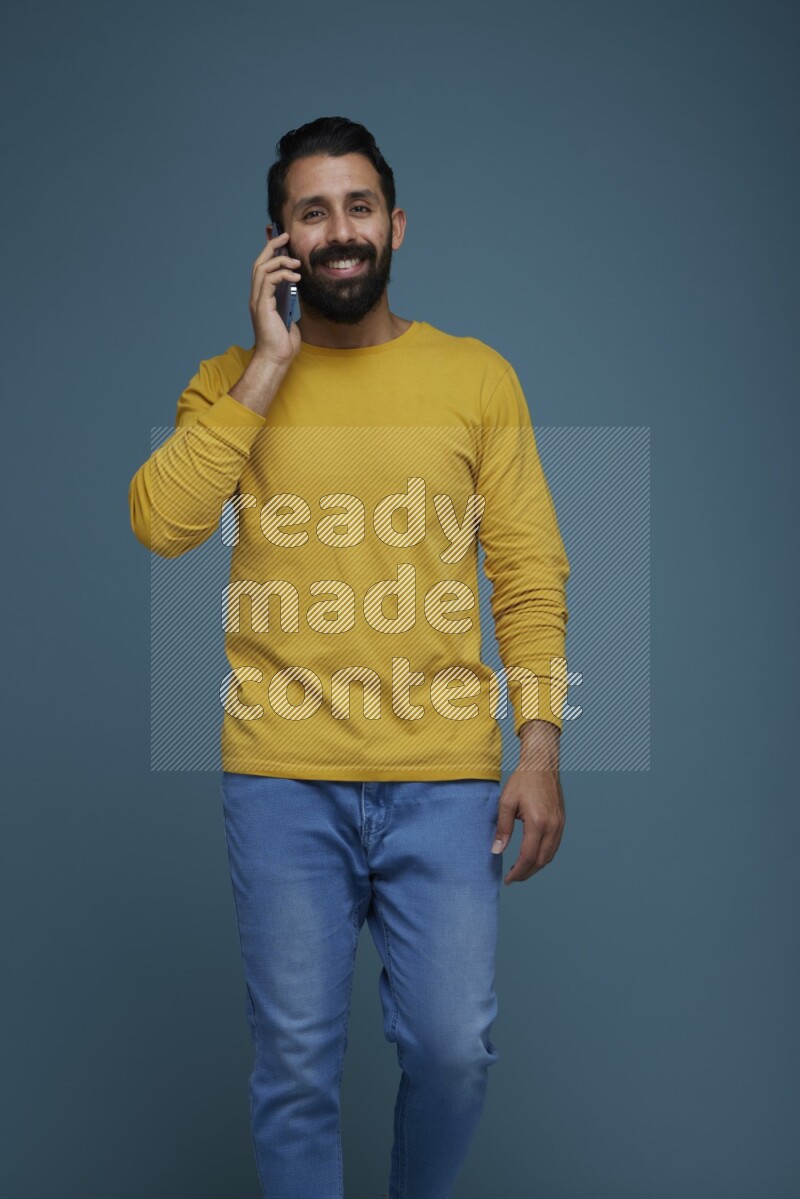 A man having a calling in a blue background wearing a yellow shirt