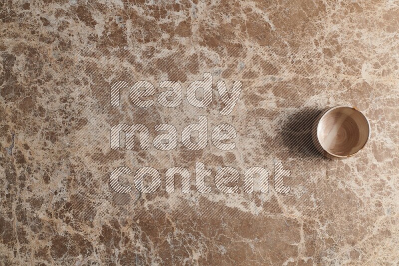 A multicolored pottery bowl on beige marble background