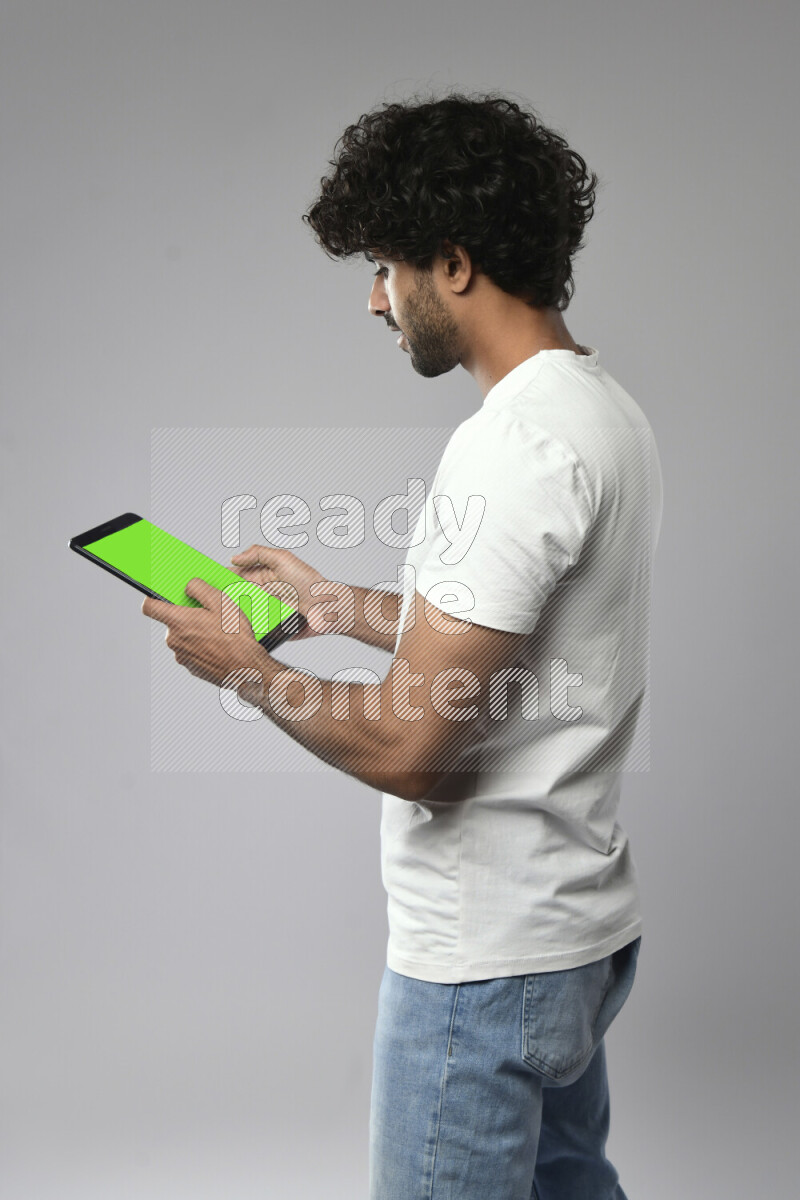 A man wearing casual standing and browsing on a tablet on white background