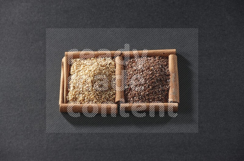 2 squares of cinnamon sticks full of flaxseeds and sesame on black flooring