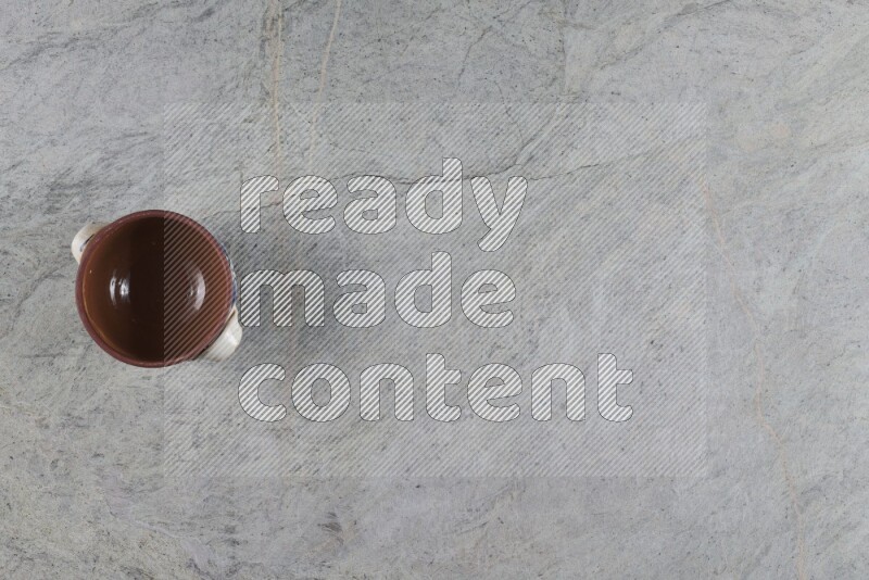 A multicolored pottery pot with its lid on grey marble background