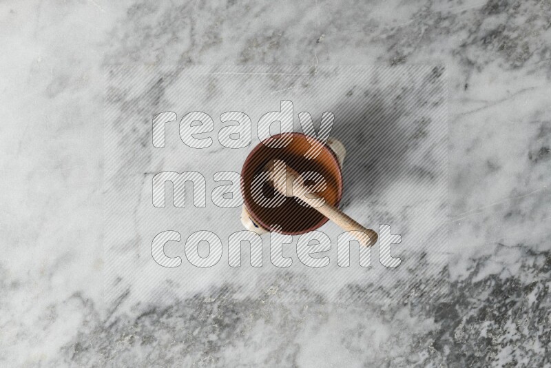 Decorative Pottery Pot with wooden honey handle in it, on grey marble flooring, Top View