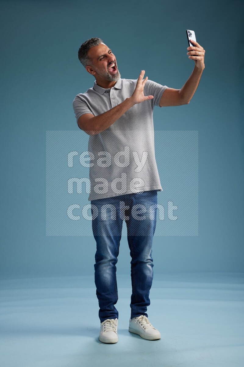 Man Standing taking selfie on blue background