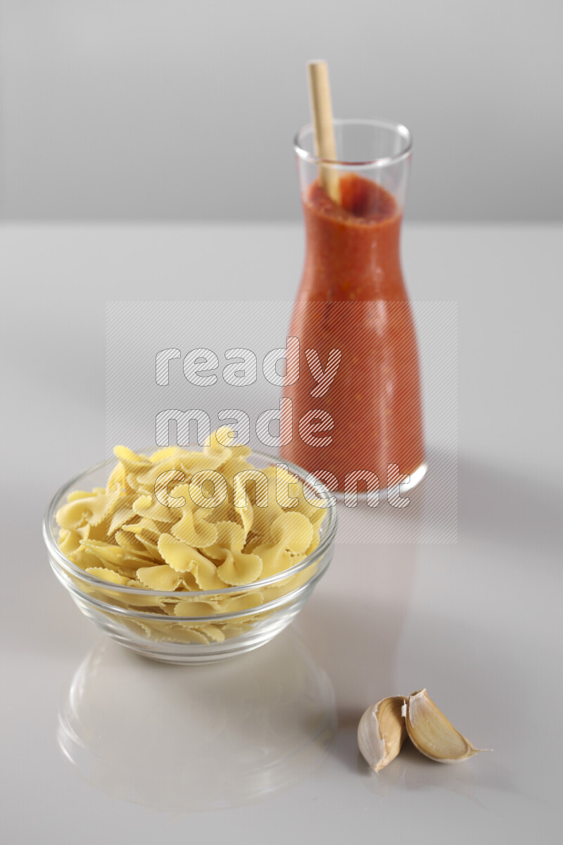 معكرونة مع صلصة طماطم مع مكونات متنوعة من الطماطم والثوم والريحان والفلفل الأحمر والفلفل الأسود والفلفل الأبيض وأوراق الغار والهيل وسنابل القمح على خلفية رمادية