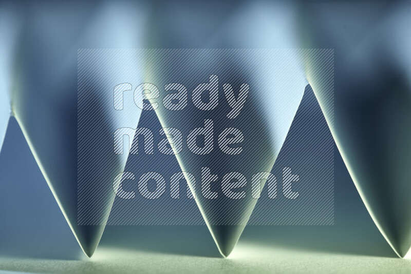 صورة مجردة مقربة تظهر طيات ورقية هندسية حادة بتدرجات اللون الأخضر والأزرق