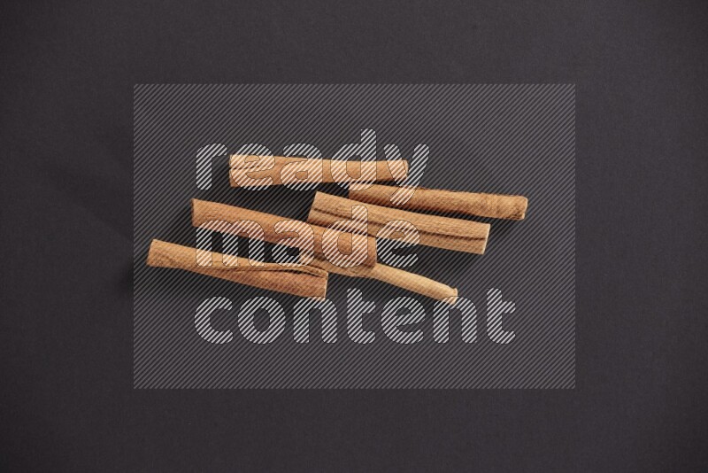 Cinnamon sticks stacked on black flooring