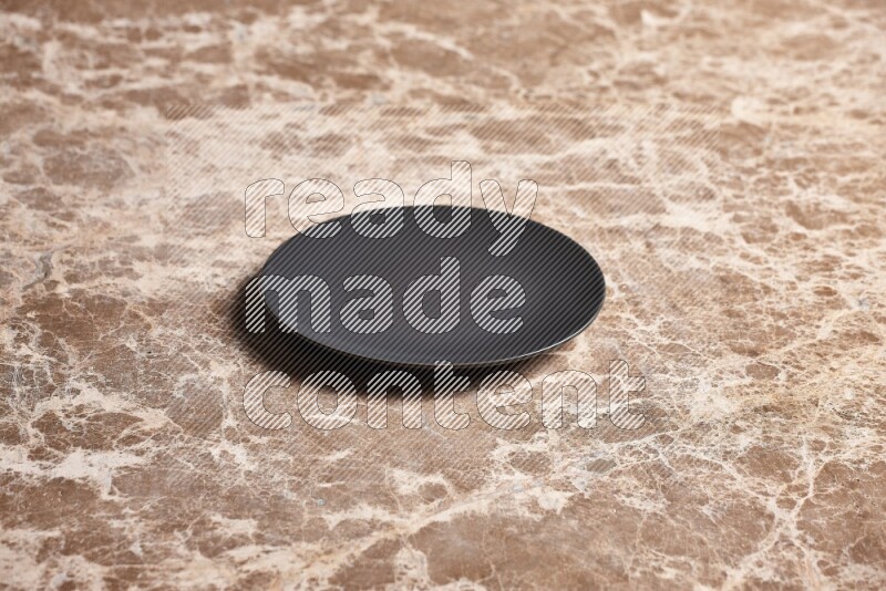 A black ceramic circular plate on beige marble background