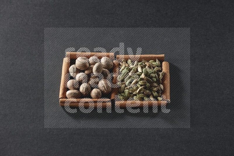 2 squares of cinnamon sticks full of nutmegs and cardamom on black flooring