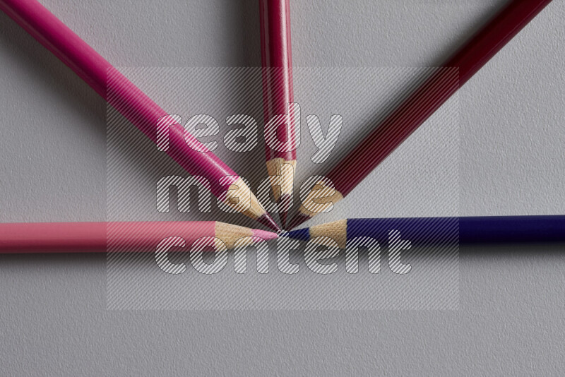 An arrangement of colored pencils in different colors on grey background