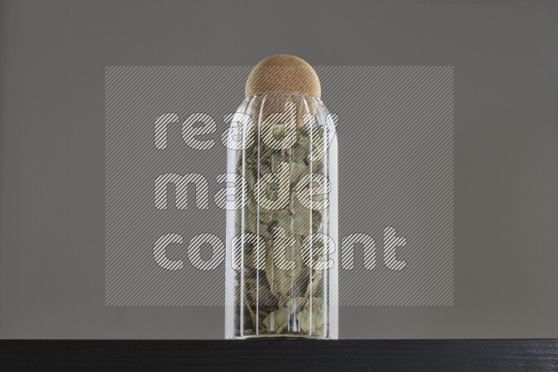Bay laurel leaves in a glass jar on black background