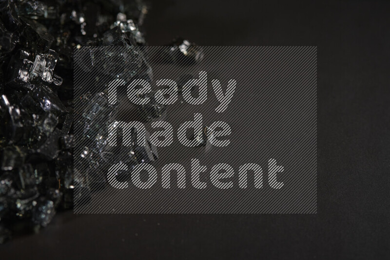 Transparent black fragments of glass scattered on a black background
