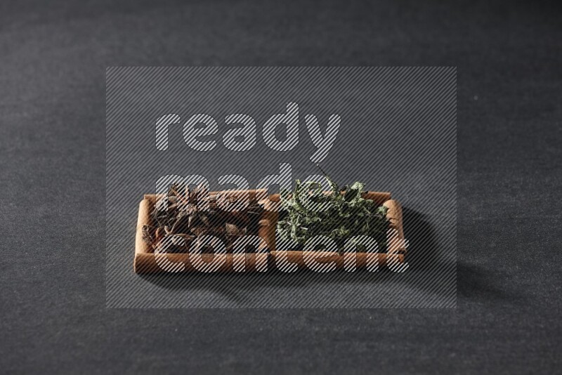 2 squares of cinnamon sticks full of star anise and dried mint leaves on black flooring