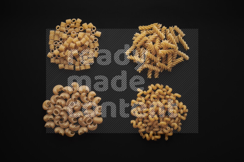 Different pasta types in bunches on black background