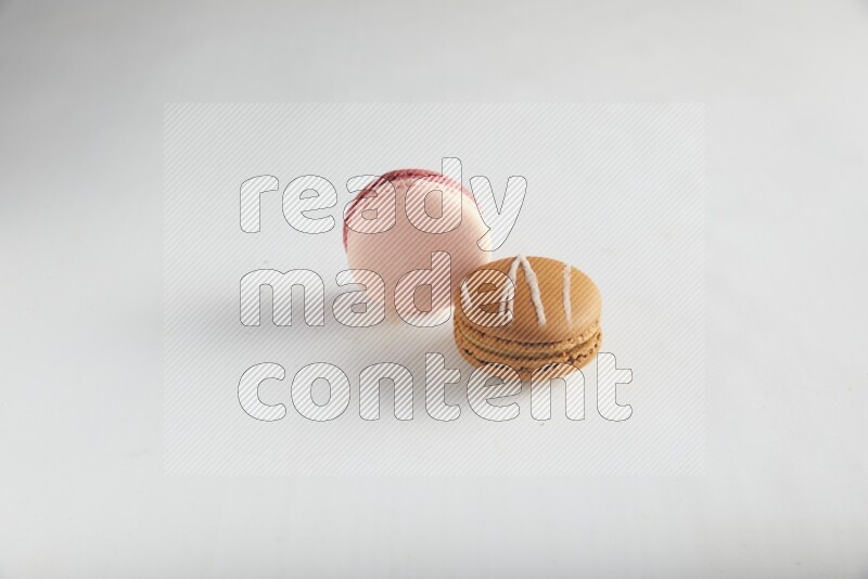 45º Shot of of two assorted Brown Irish Cream, and Pink Litchi Raspberry macarons on white background