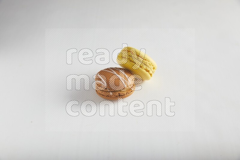45º Shot of of two assorted Brown Irish Cream, and Yellow Lemon macarons on white background