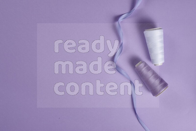 A white and purple collection of sewing and tailoring tools arranged on a purple background