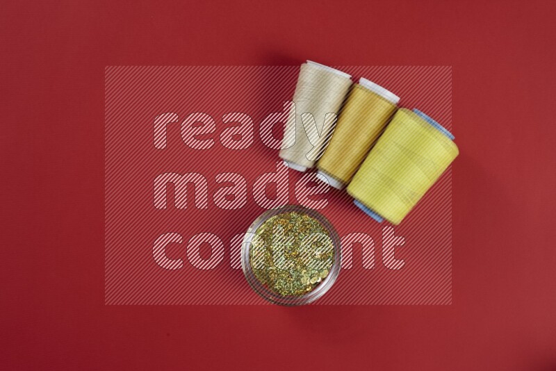 مجموعة من أدوات الخياطة والتفصيل صفراء اللون على خلفية حمراء