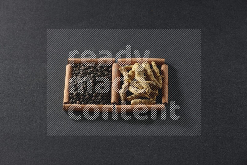 2 squares of cinnamon sticks full of black peppers and turmeric fingers on black flooring