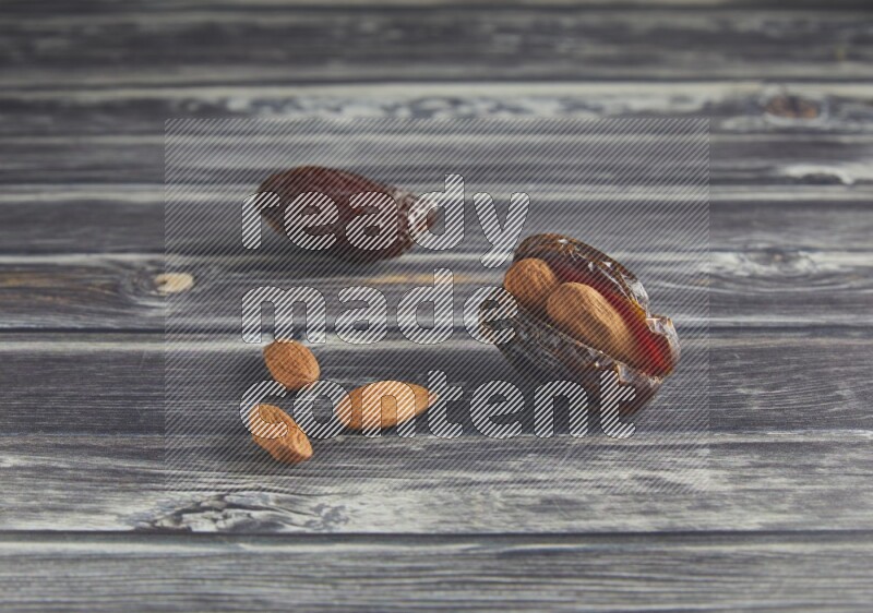 two almond stuffed madjoul dates on a wooden grey background