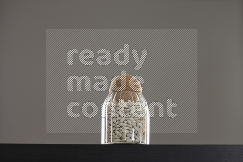 White beans in a glass jar on black background