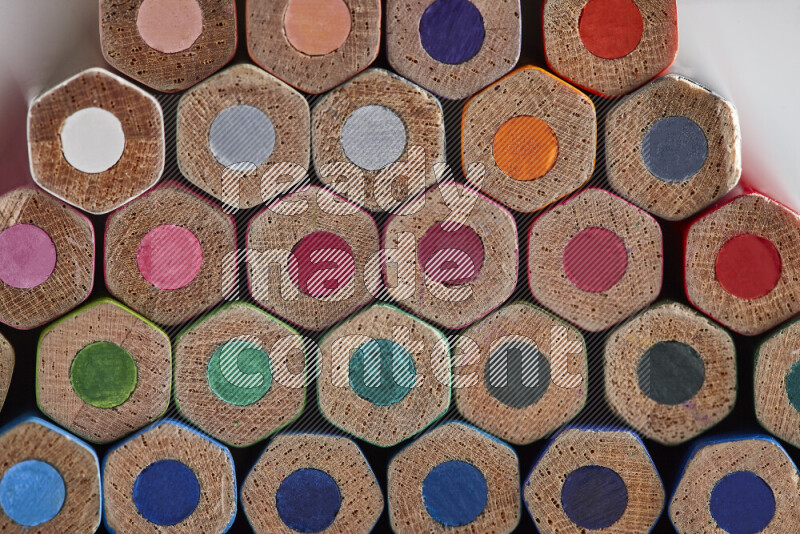 A close-up of the tips of colored pencils arranged in a bundle on white background