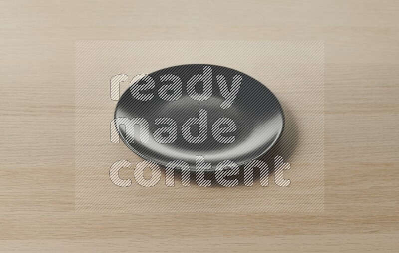 A black ceramic circular plate on light wooden background