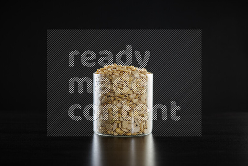 Crushed beans in a glass jar on black background