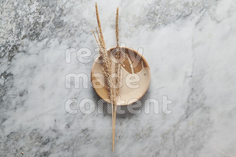 Wheat stalks on multicolored pottery plate on grey marble background