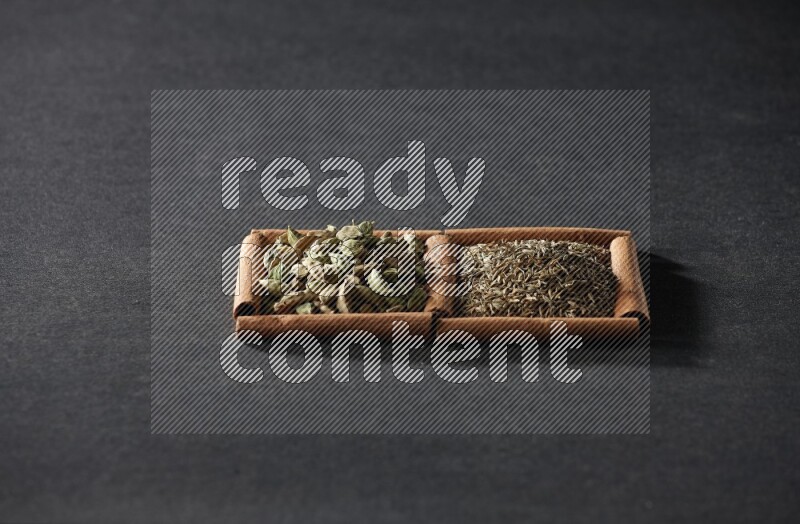 2 squares of cinnamon sticks full of cumin and cardamom on black flooring