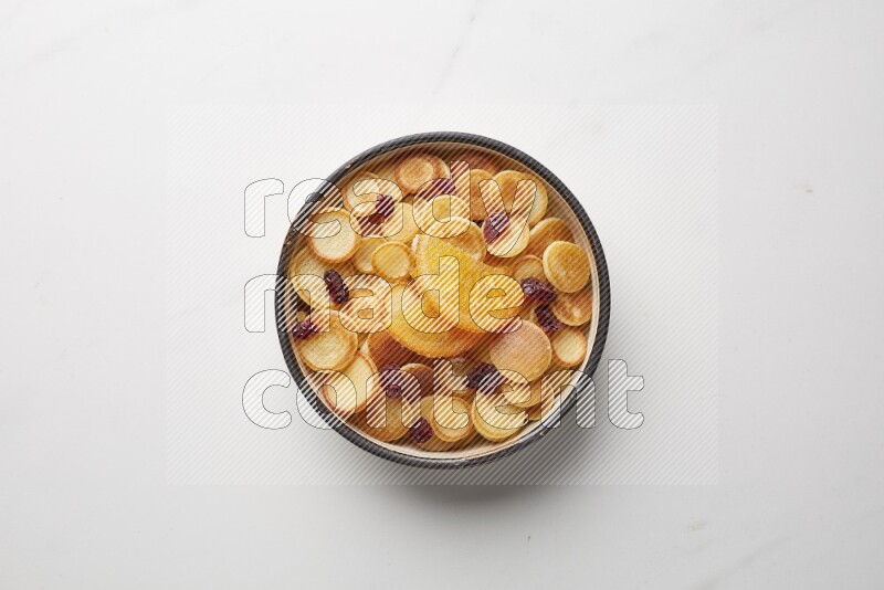 Top-view shot of orange candy cereal pancakes in a round bowl on white background