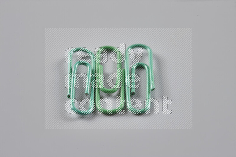 Green paper clips isolated on a grey background