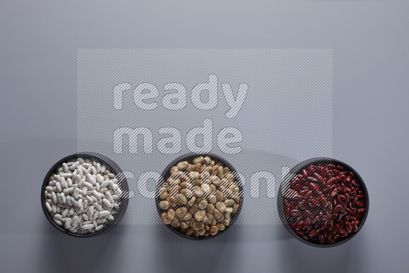 Legumes in pottery bowls on light grey background