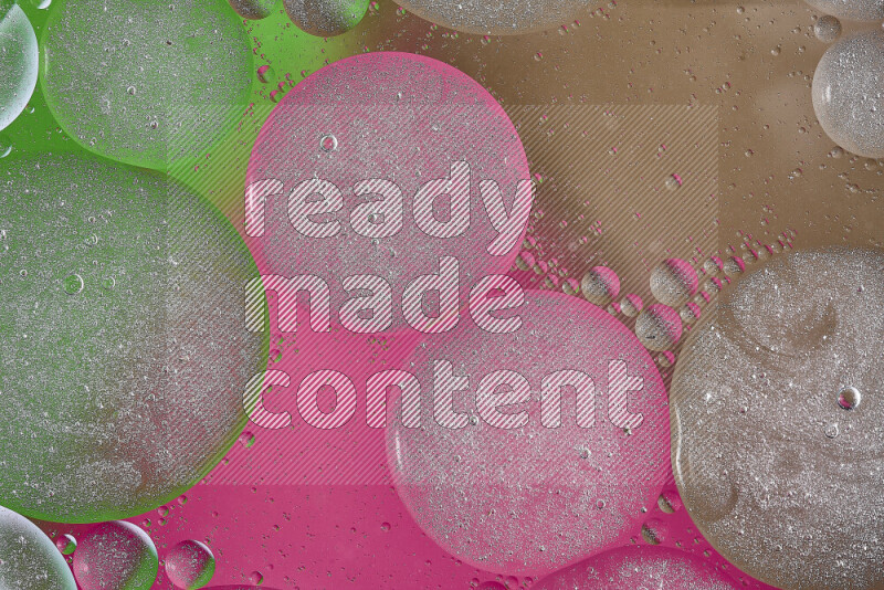 Close-ups of abstract oil bubbles on water surface in shades of brown, green and pink
