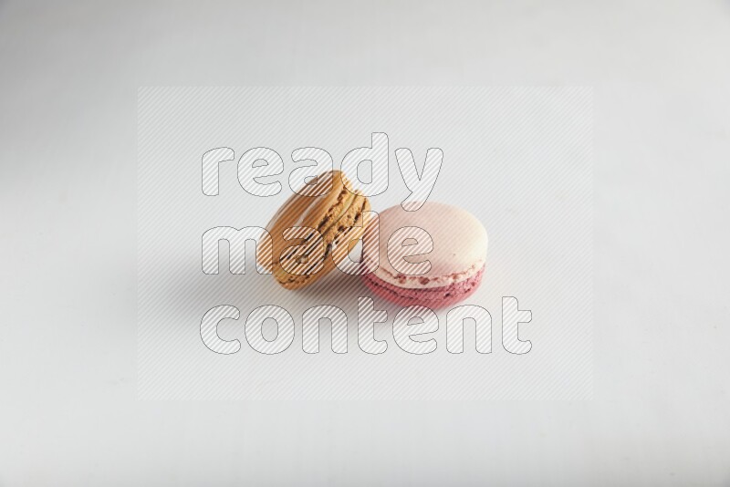 45º Shot of of two assorted Brown Irish Cream, and Pink Litchi Raspberry macarons on white background