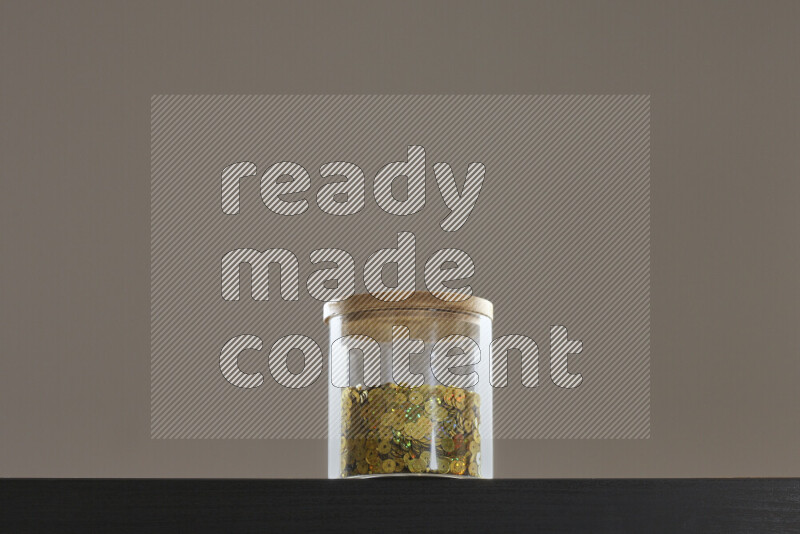 Sequins in a glass jar on black background