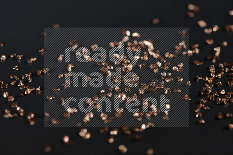 Bronze shimmering fragments of glass scattered on a black background