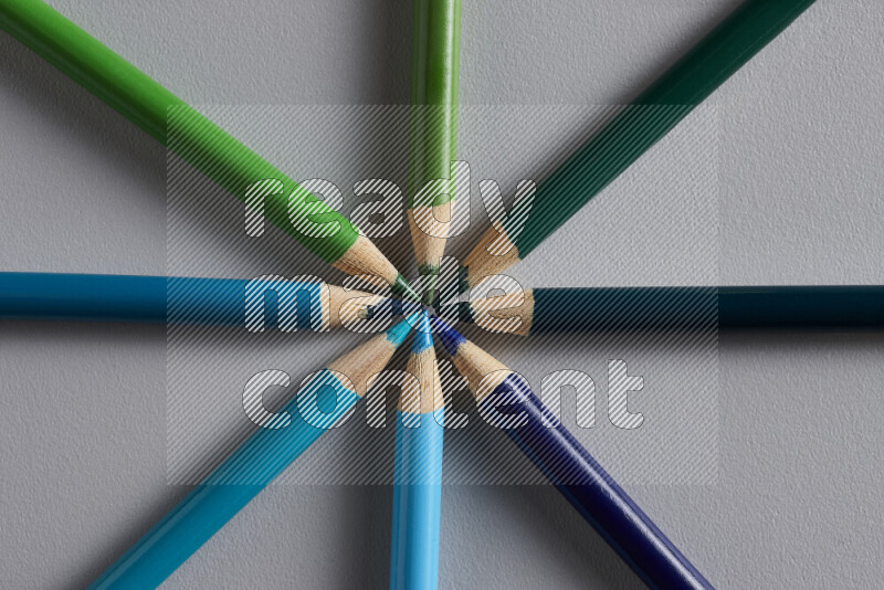 An arrangement of colored pencils in different colors on grey background