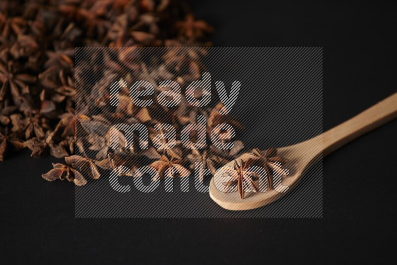 Star Anise in a wooden spoon and spreading on a black flooring