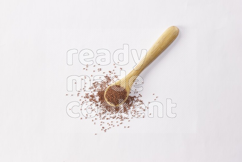 A wooden spoon full of garden cress seeds on a white flooring