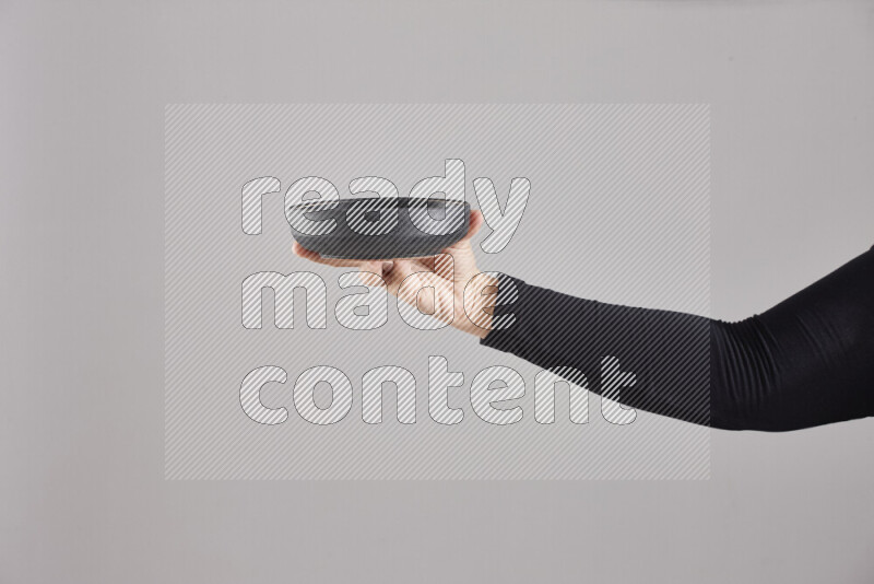 A woman in black abaya holding different pottery essentials in different positions