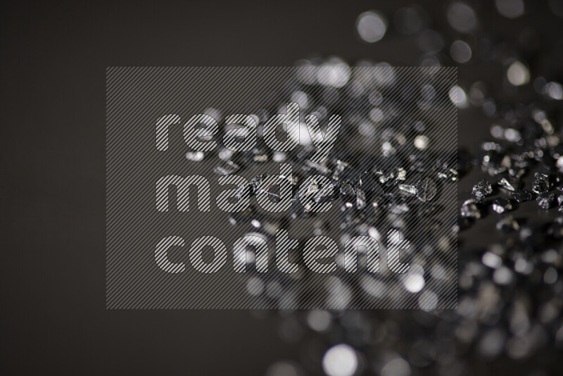 Black shimmering fragments of glass scattered on a black background