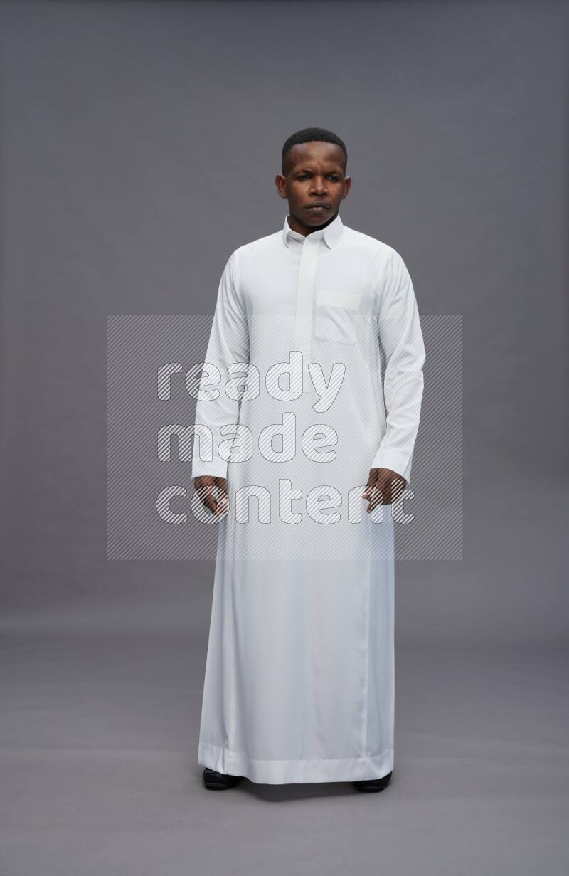 Saudi man wearing thob standing interacting with the camera on gray background