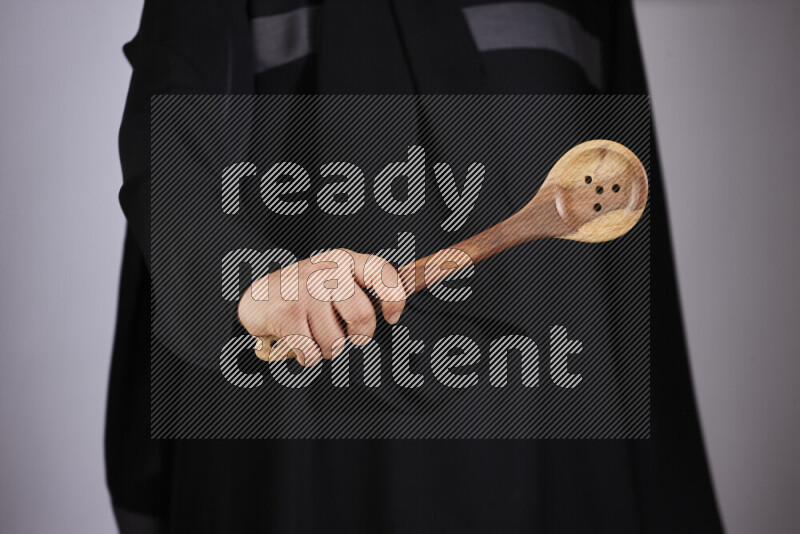 A woman in black abaya holding different wooden essentials in different positions